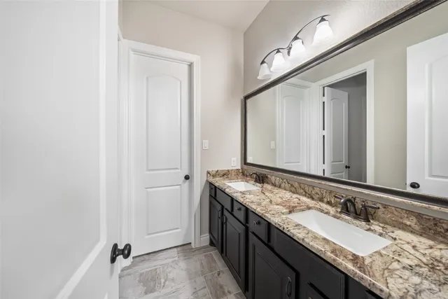 a bathroom with a granite countertop double vanity sink and a mirror