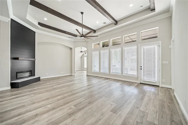 a view of an empty room with wooden floor and a ceiling fan
