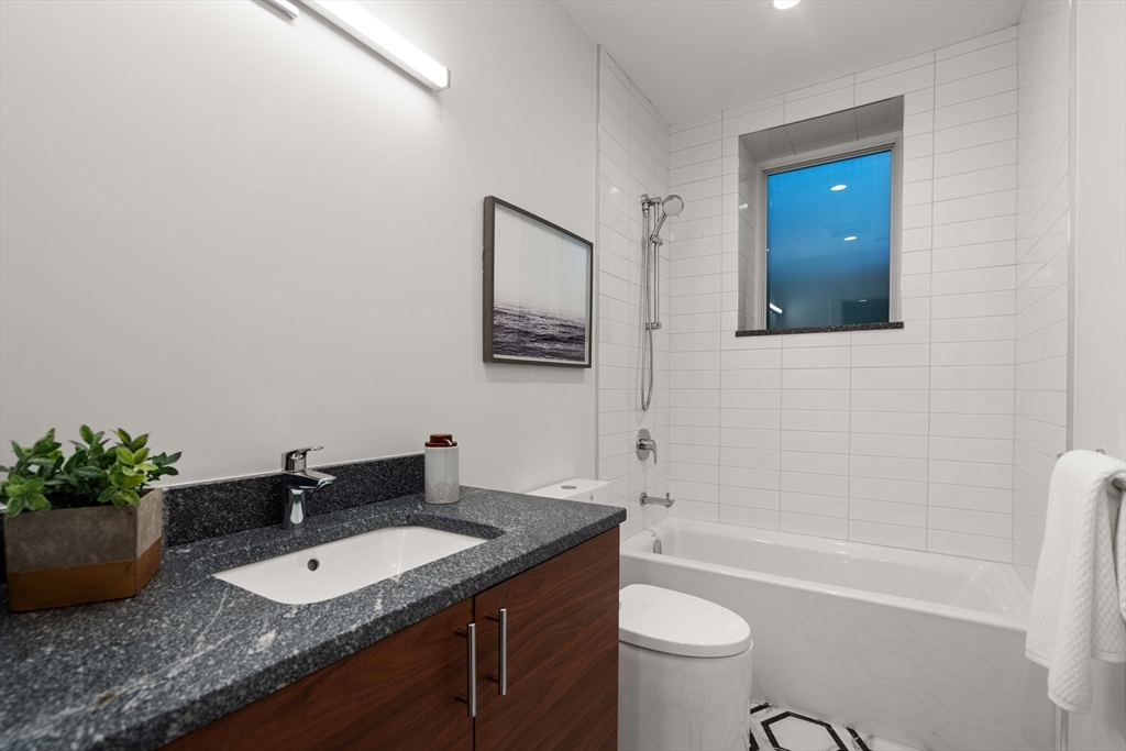 110 Harvard Street, Unit A Newton, MA 02460 - Photo 10 of 30 a bathroom with a granite countertop sink a toilet a mirror and shower