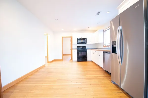 a large white kitchen with stainless steel appliances granite countertop a refrigerator and a sink