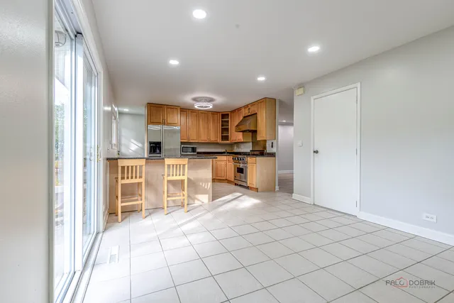a view of kitchen with kitchen island granite countertop a refrigerator and a sink