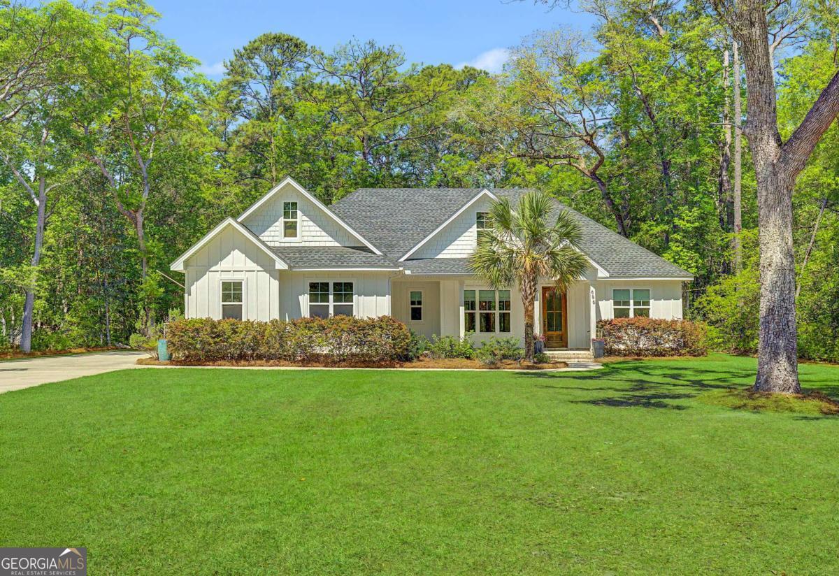 a front view of a house with a garden and trees