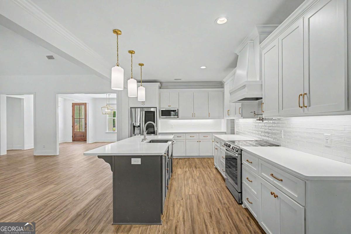 656 Sanderling Trace Waverly, GA 31565 - Photo 15 of 71 a kitchen with stainless steel appliances kitchen island granite countertop a sink stove and wooden floors