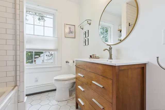 a bathroom with a toilet a sink a mirror and a window