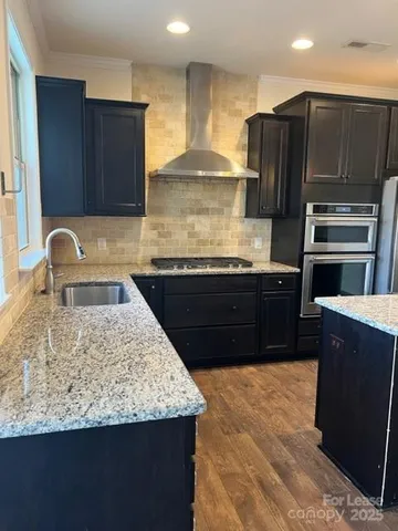 a kitchen with kitchen island granite countertop wooden cabinets a refrigerator and a sink