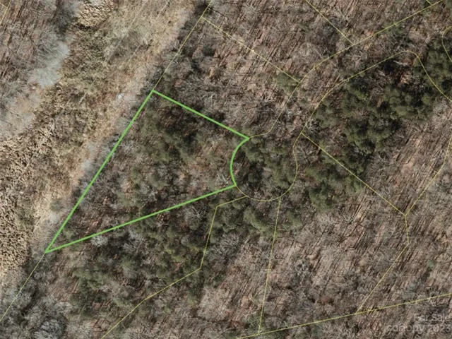 a view of a dry yard with wooden fence and basketball court