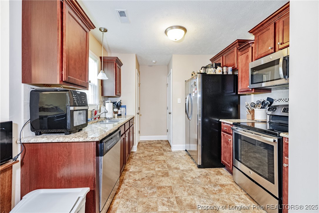 3453 Thrower Road Hope Mills, NC 28348 - Photo 7 of 24 a kitchen with stainless steel appliances granite countertop a refrigerator a stove and a sink