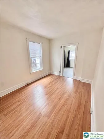 a view of an empty room with a window and wooden floor