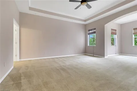 an empty room with windows and ceiling fan