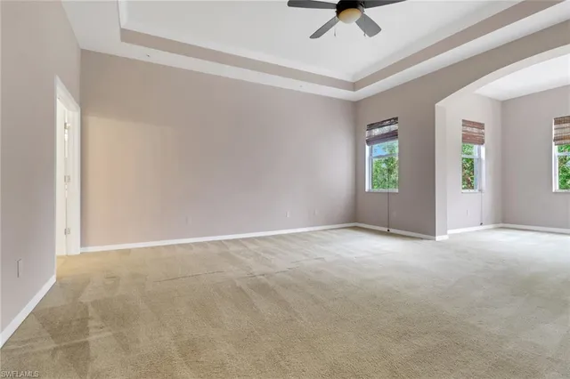 an empty room with windows and ceiling fan