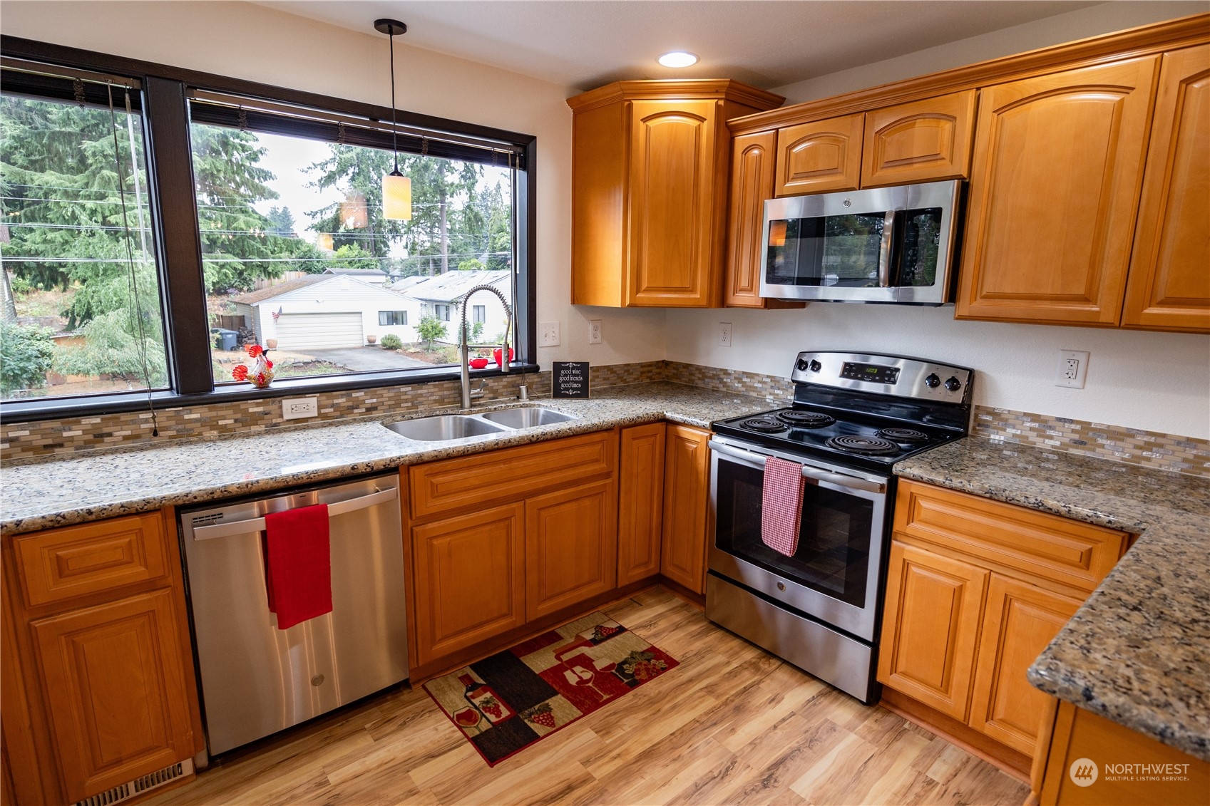 129 Del Monte Avenue Fircrest, WA 98466 - Photo 14 of 38 a kitchen with stainless steel appliances granite countertop wooden cabinets a stove a sink and a large window