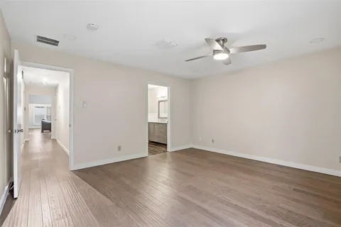 an empty room with wooden floor fan and windows