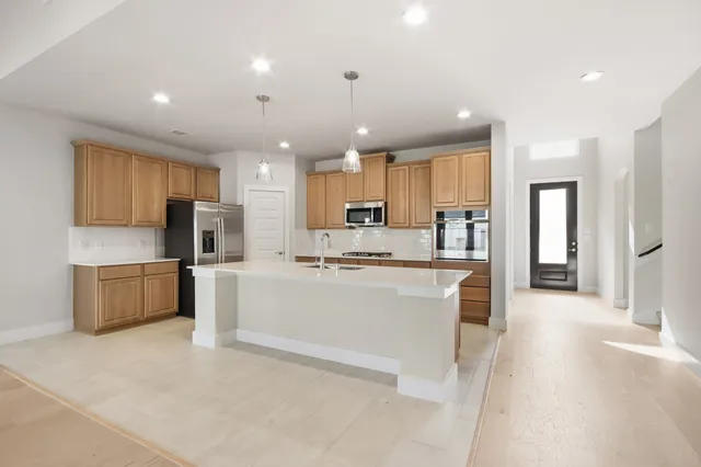 a large kitchen with kitchen island a sink a center island stainless steel appliances and a cabinets