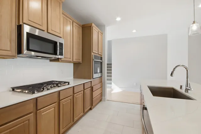 a kitchen with stainless steel appliances a stove microwave and sink