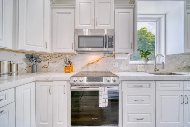a kitchen with granite countertop white cabinets and a stove