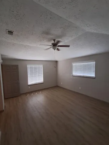 an empty room with a wooden floor and windows
