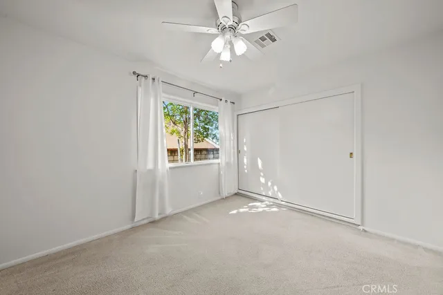 an empty room with windows and fan