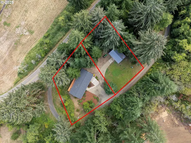 an aerial view of a house with a yard wooden fence and large trees