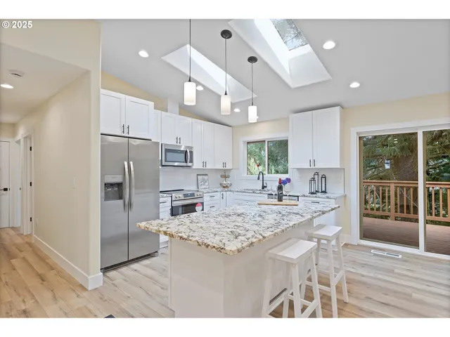 a kitchen with stainless steel appliances kitchen island granite countertop a refrigerator and a sink
