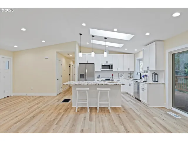 a kitchen with a sink granite counter tops and a view of living room