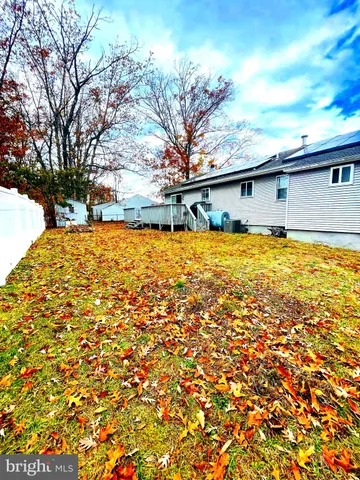 a backyard of a house with large trees and covered with wooden fence