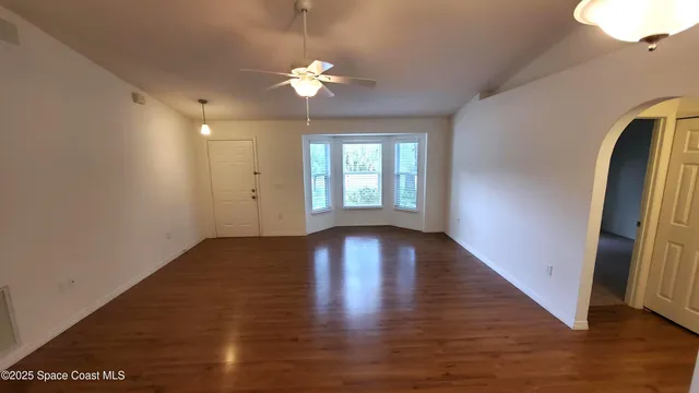a view of an empty room with wooden floor and a window