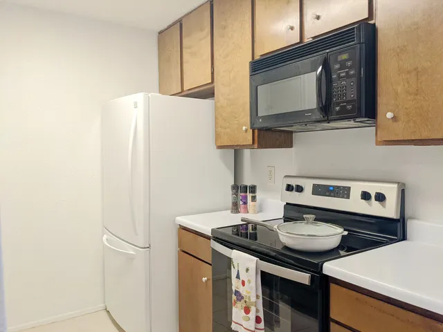 a kitchen with stainless steel appliances a sink a stove a microwave a refrigerator and cabinets