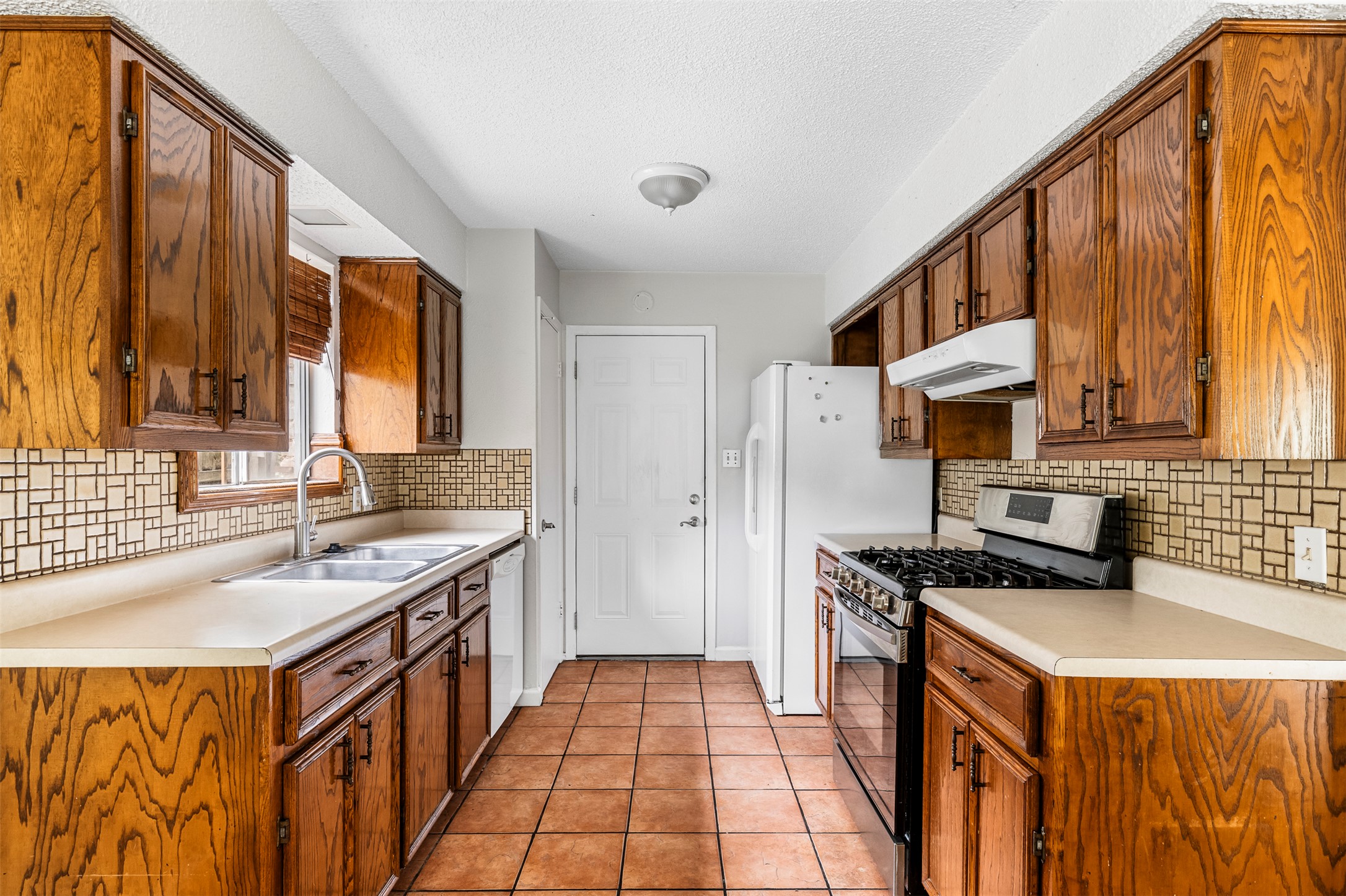 7506 Glenhill Road Austin, TX 78752 - Photo 6 of 24 Well-lit galley kitchen offers ample cabinetry and functional appliances.