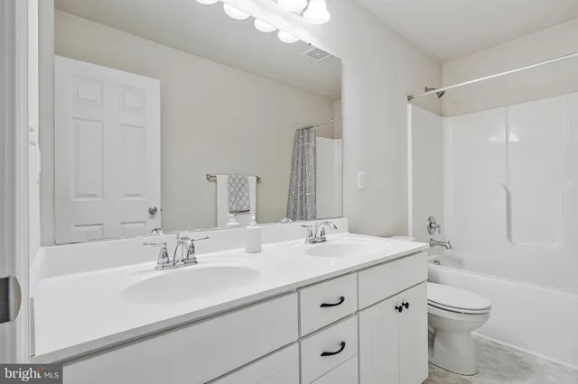 a bathroom with a double vanity sink toilet mirror and bathtub