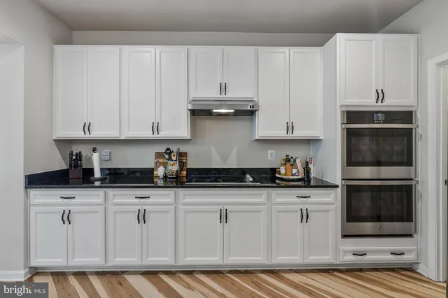 a kitchen with granite countertop white cabinets and stainless steel appliances