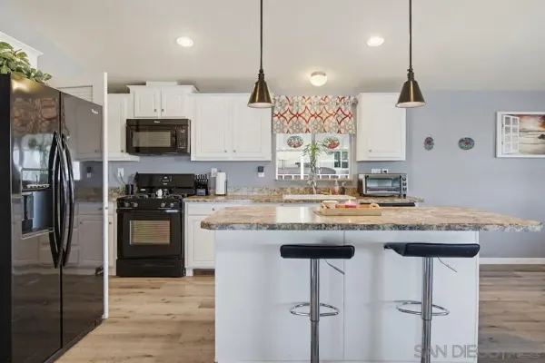 a open kitchen with stainless steel appliances granite countertop a kitchen island a stove a table and chairs