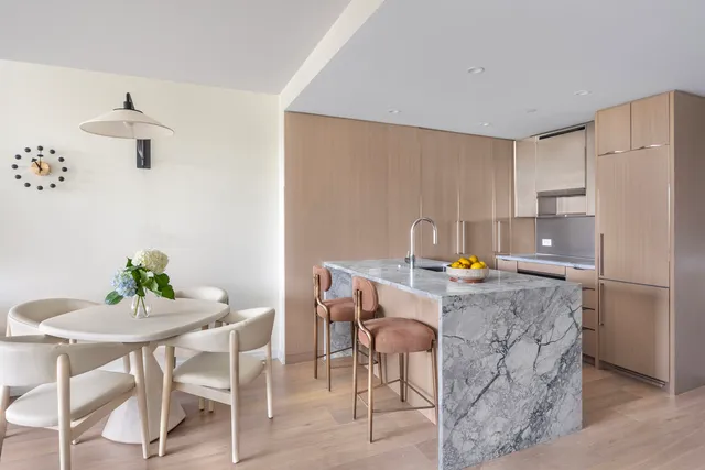 a kitchen with stainless steel appliances a refrigerator a stove a dining table and chairs with wooden floor