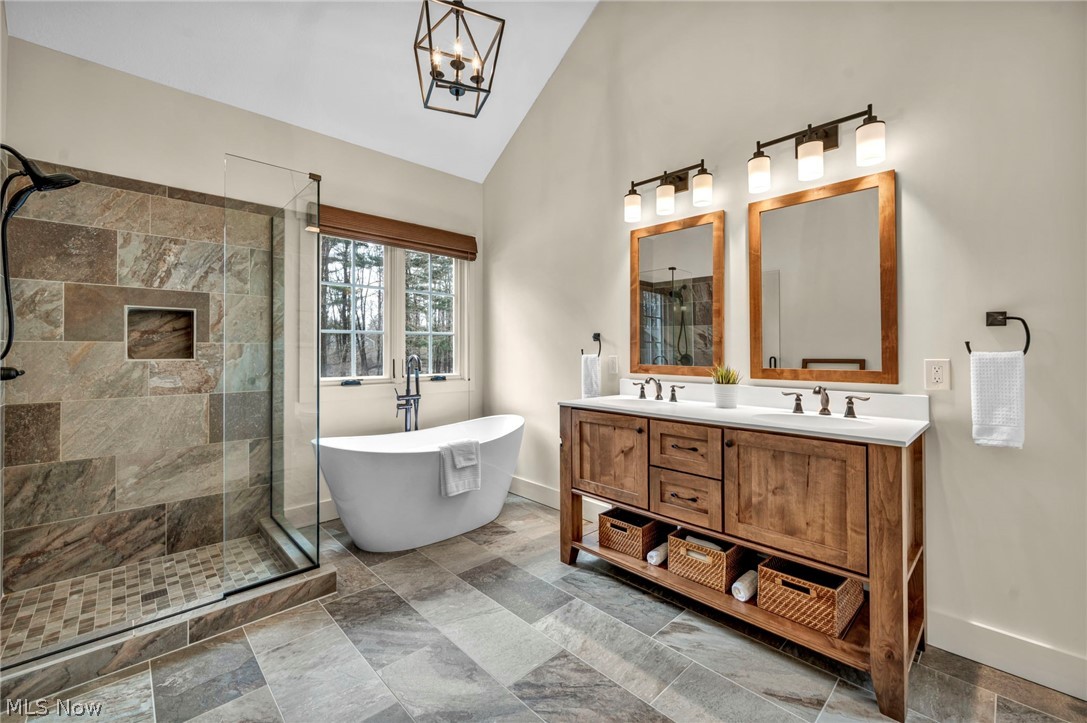 11295 Sutton Place Chardon, OH 44024 - Photo 23 of 50 Bathroom with tiled shower, double vanity, lofted ceiling, a freestanding tub, and suspended lighting