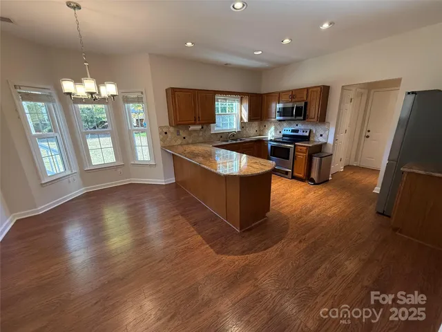 a kitchen with stainless steel appliances granite countertop a refrigerator a stove top oven a sink dishwasher and wooden floor
