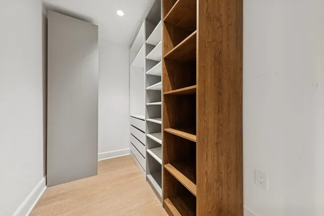 a view of walk in closet with clothes and shoes