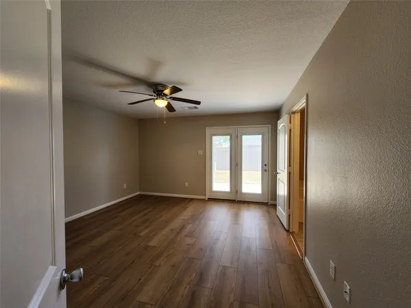 a view of an empty room with wooden floor and a window