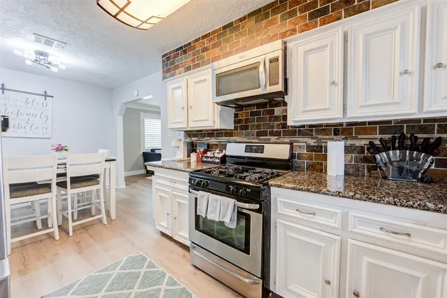 a kitchen with stainless steel appliances granite countertop a stove a sink and a microwave