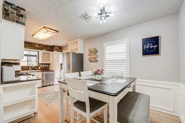 a kitchen with a refrigerator a stove a sink dishwasher with a dining table and chairs