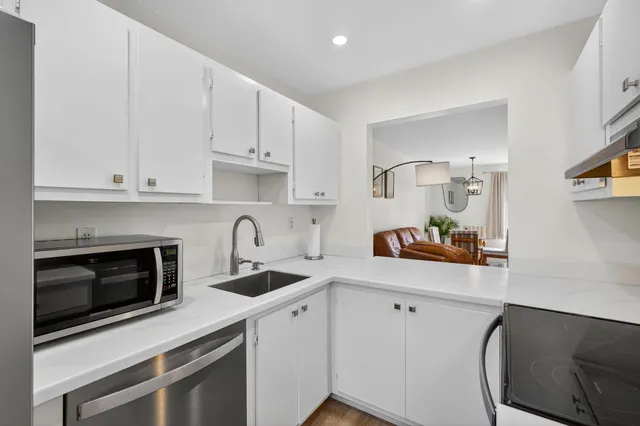 a kitchen with granite countertop white cabinets and white appliances