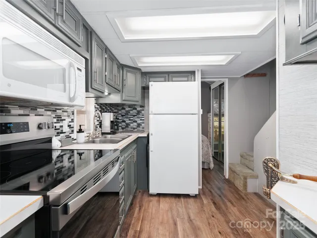 a kitchen with a refrigerator a sink and wooden floor