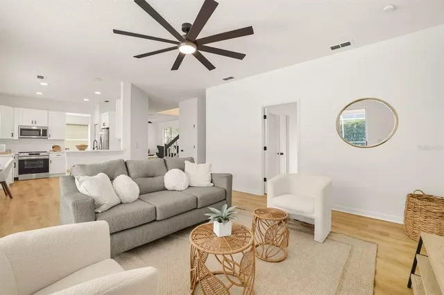 a living room with furniture kitchen view and a wooden floor