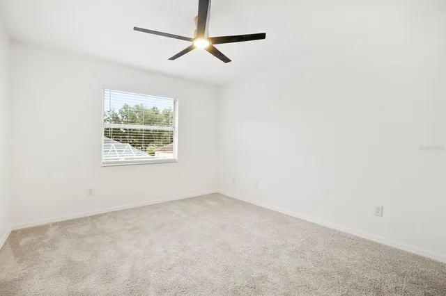 an empty room with a window and a ceiling fan