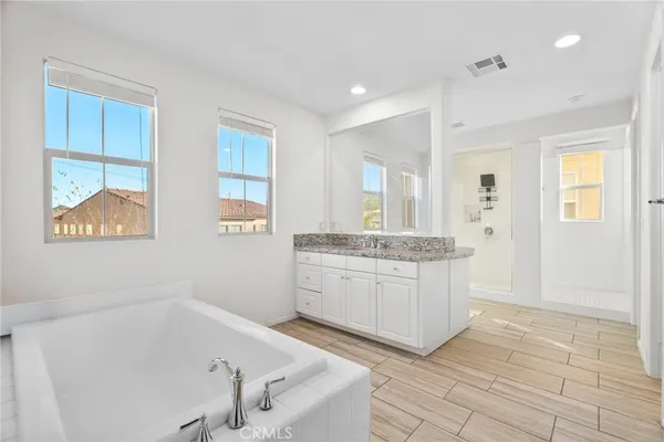 a bathroom with a granite countertop sink a mirror and a bathtub