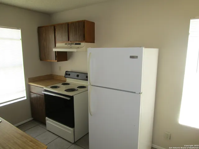 a white refrigerator freezer and a stove sitting inside of a kitchen