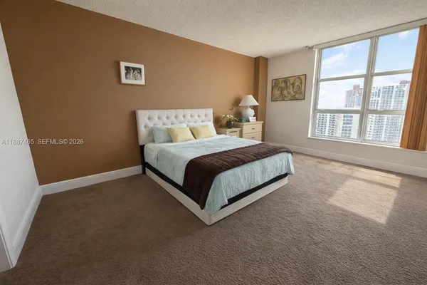 a bedroom with a bed lamp and a large window