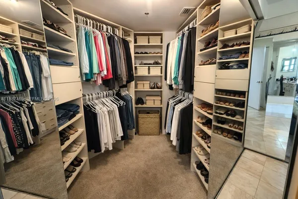 a view of walk in closet with clothes and shoes