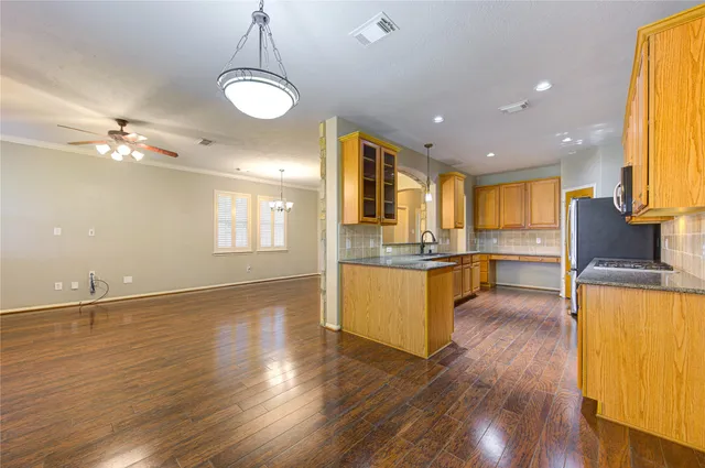 a large kitchen with a center island wooden floor stainless steel appliances and living room view