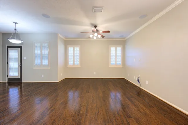 an empty room with wooden floor ceiling fan and windows