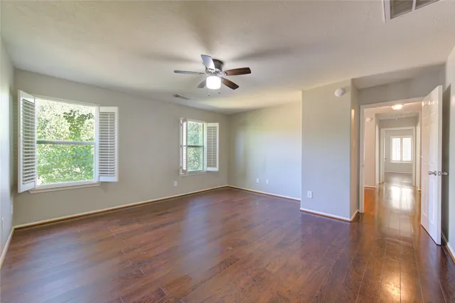 a view of an empty room with a window and wooden floor