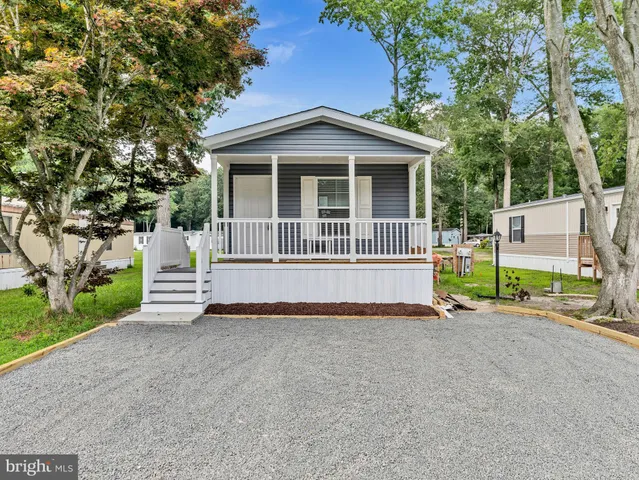 a view of a house with a small yard and large trees
